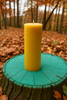 Yellow candle on a green wooden stump in a forest setting