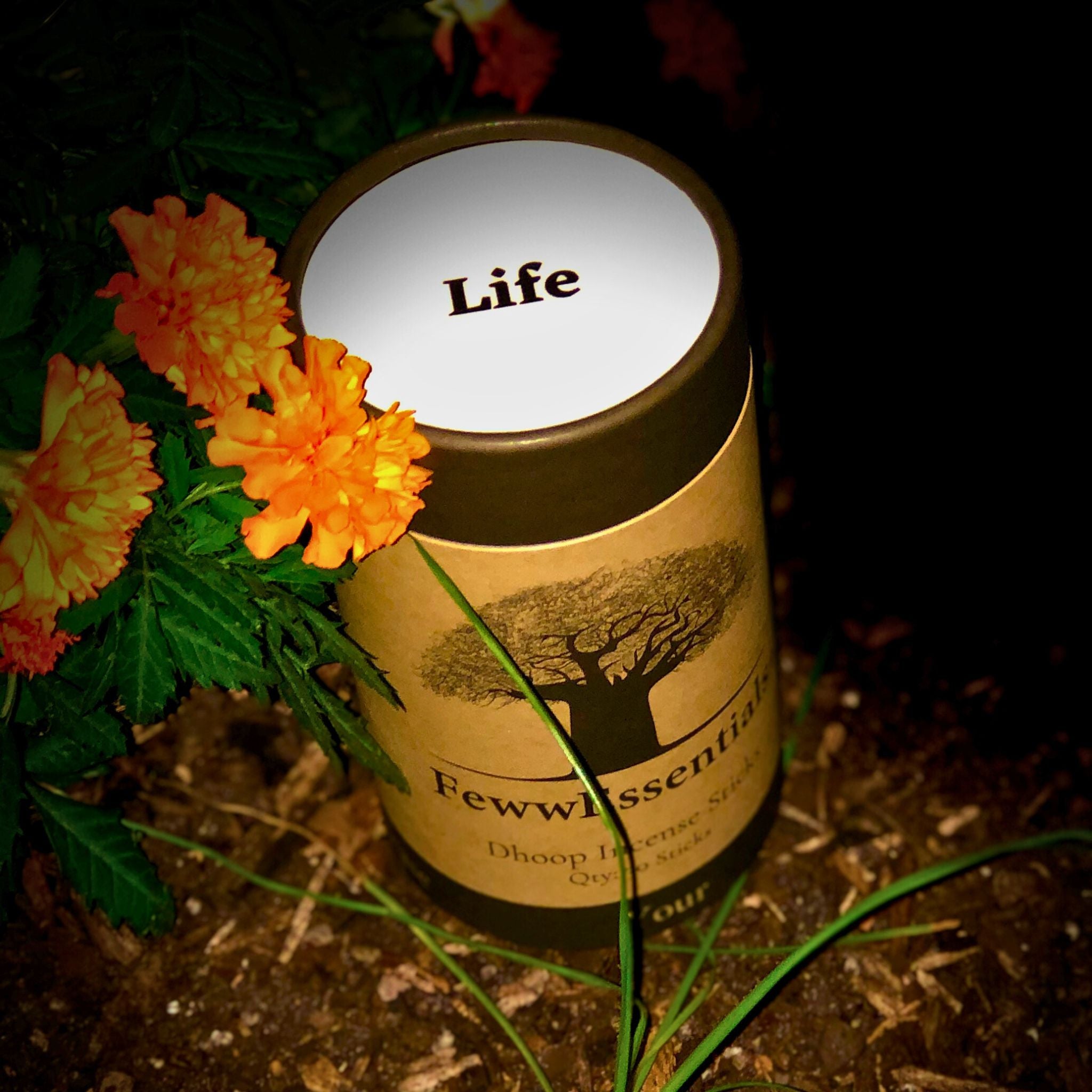 FewwEssentials Dhoop Incense Sticks labeled Life placed among vibrant orange marigold flowers in a garden setting.