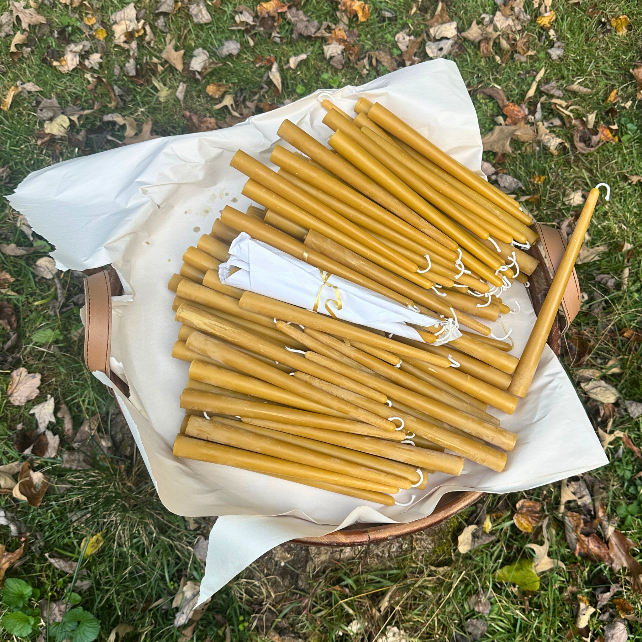 FewwEssentials hand-dipped pure beeswax taper candles with cotton wicks, natural golden color, displayed outdoors.