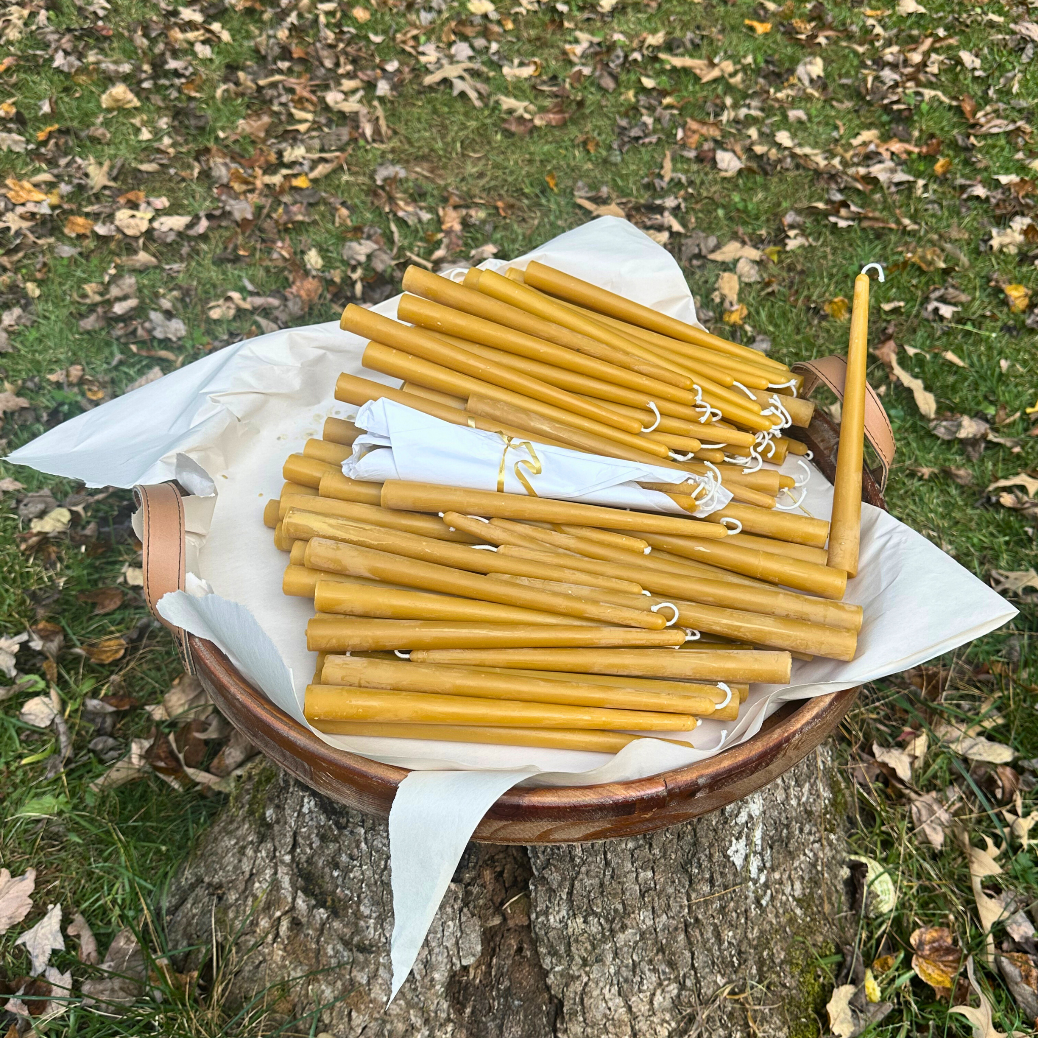 FewwEssentials hand-dipped pure beeswax taper candles with cotton wicks, natural golden color, displayed outdoors.