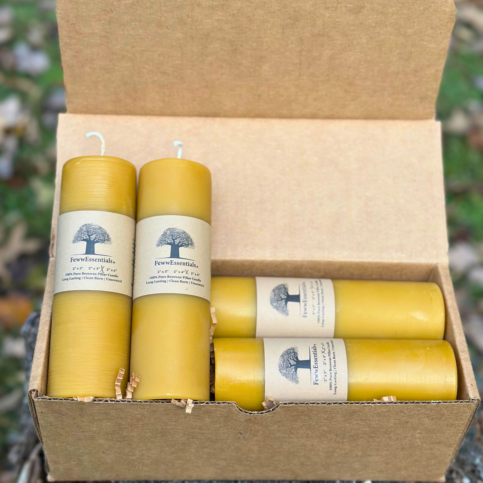 FewwEssentials handcrafted 2x6 beeswax pillar candles, 4-pack in sustainable kraft packaging with natural golden tone.