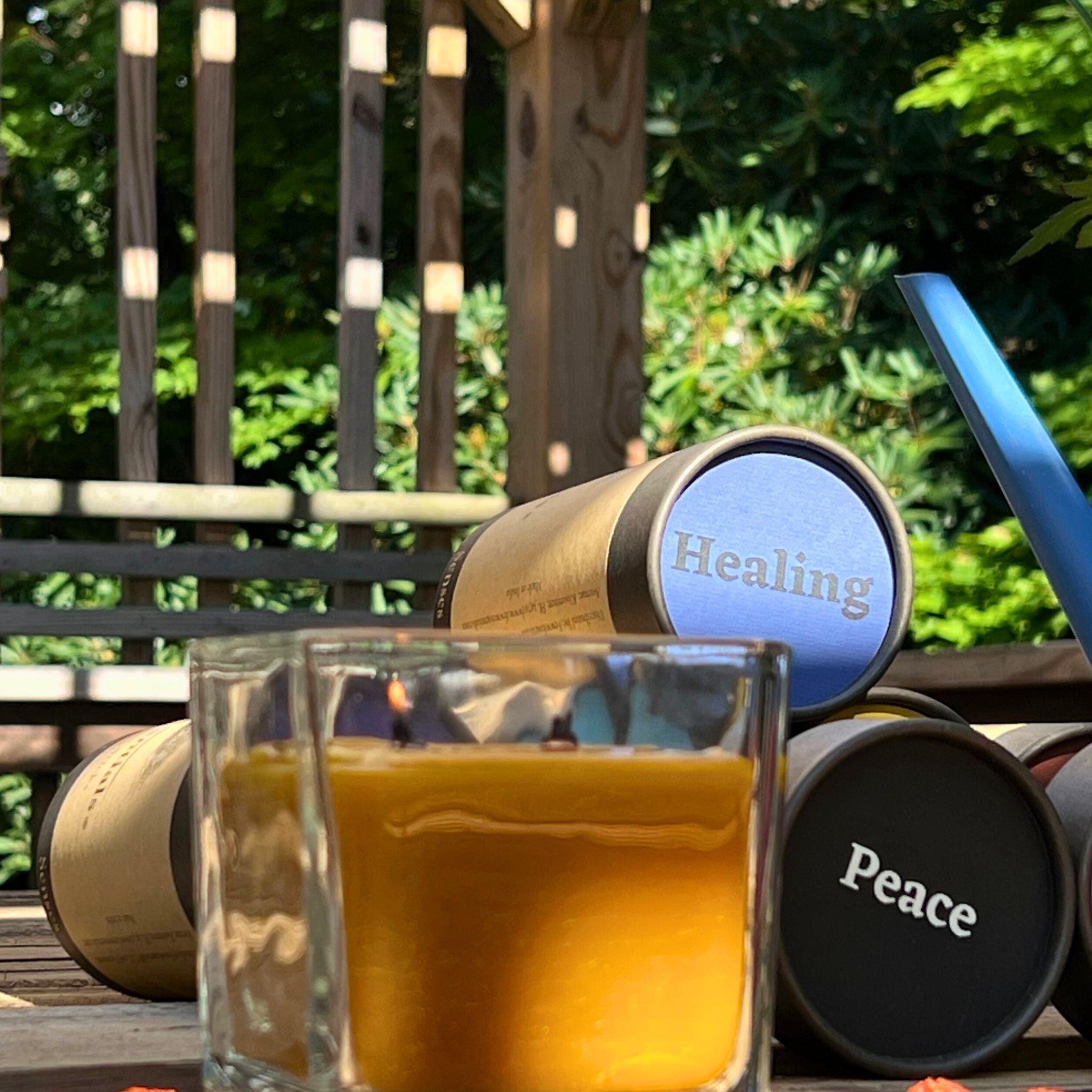 A patio scene with a square glass candle in the foreground and FewwEssentials Dhoop Incense Sticks labeled Healing and Peace in the background.