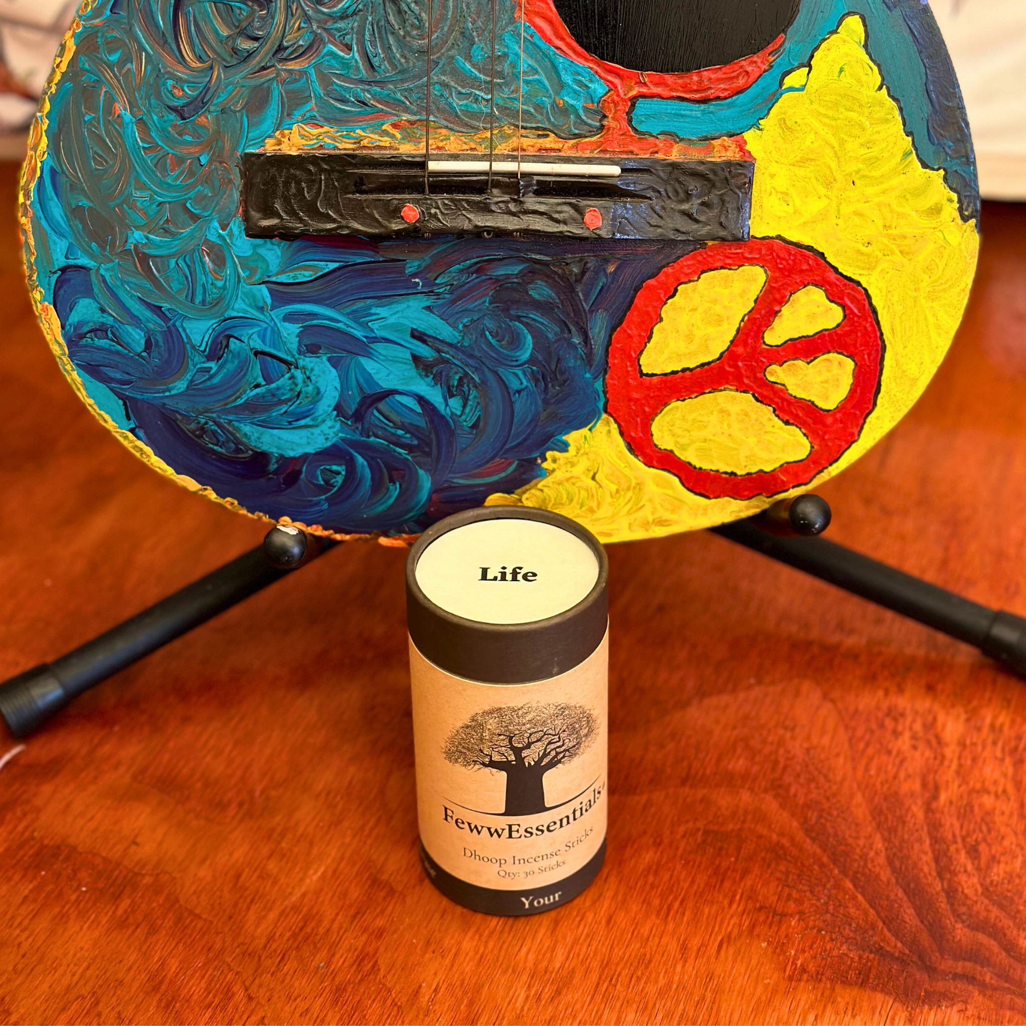 FewwEssentials Dhoop Incense Sticks labeled Life placed in front of a vibrantly painted guitar on a wooden table.